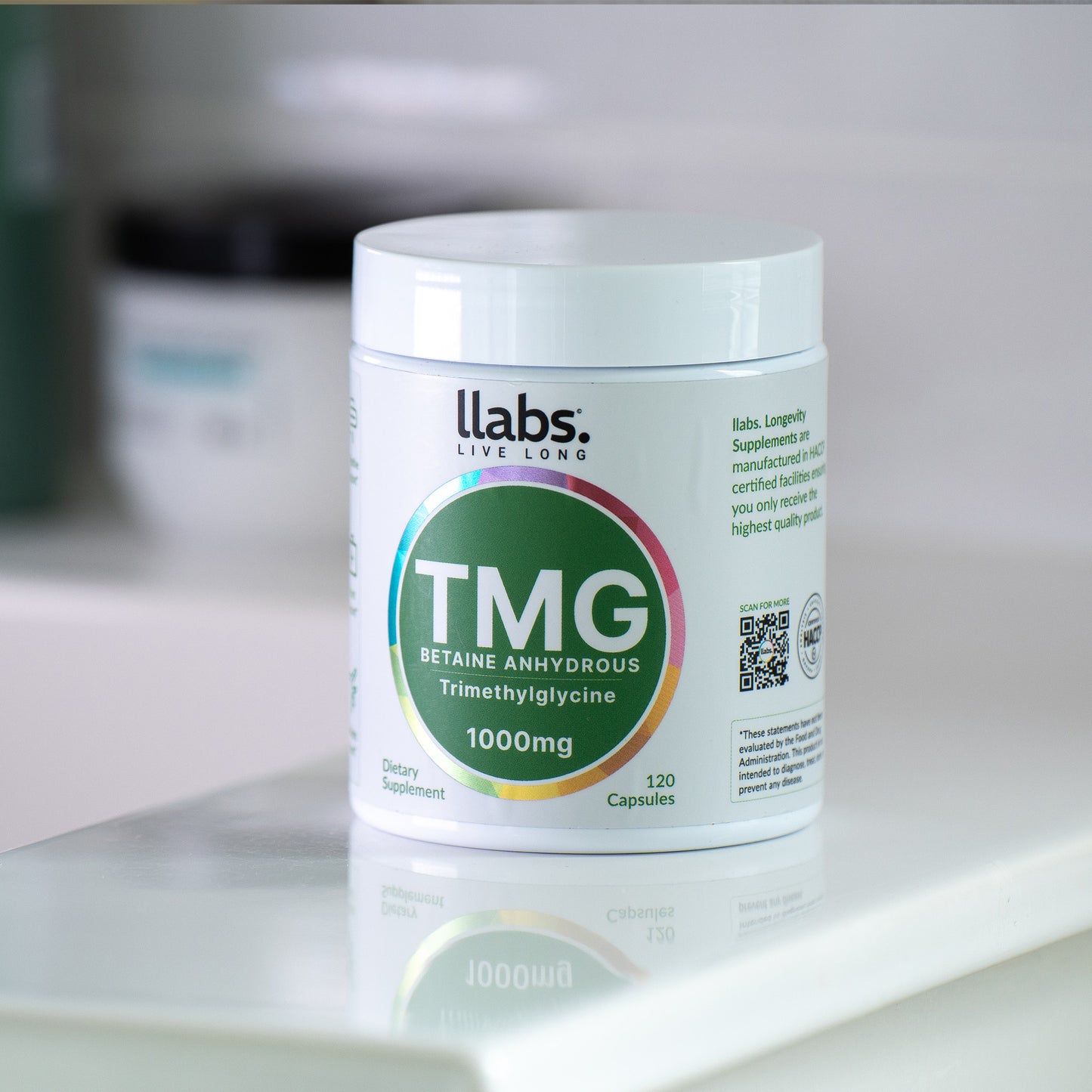 A container of llabs. TMG Supplement (Betaine) capsules is placed on a countertop. The label indicates it contains 120 capsules, each 1000mg, to enhance your daily routine.