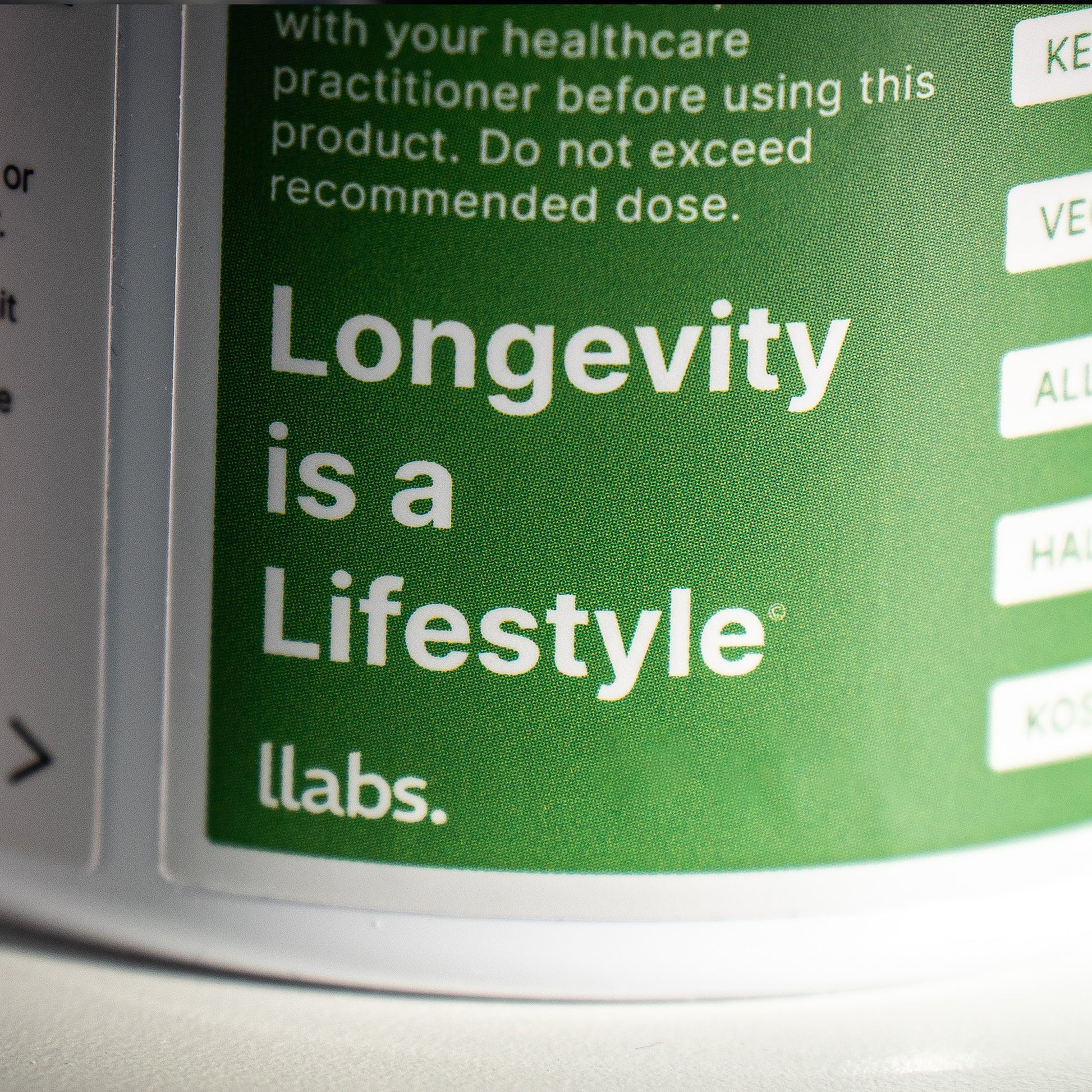 Close-up of a green label with the white text "Longevity is a Lifestyle® llabs.", adjacent to other partially visible text on the left, enhancing your daily routine with llabs. TMG Supplement (Betaine) benefits.